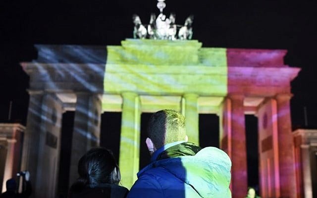 A couple watches as the colors of the Belgian flag are projected on to the Brandenburg Gate in Berlin as the German capital shows its solidarity following the Brussels attacks on March 22, 2016. (AFP / ODD ANDERSEN)