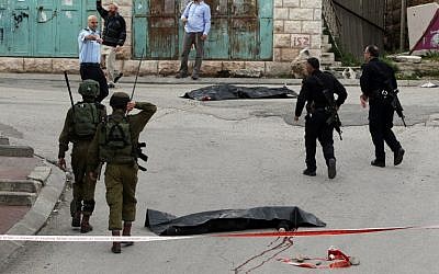 Israeli soldiers and police surround the bodies of two Palestinians who were killed after wounding an Israeli soldier in a knife attack, an army spokeswoman said, at the entrance to the heavily guarded Jewish settler enclave of Tel Rumeida in the center of the West Bank city of Hebron on March 24, 2016. (AFP / HAZEM BADER) Israeli soldiers and police surround the bodies of two Palestinians who were killed after wounding an Israeli soldier in a knife attack, an army spokeswoman said, at the entrance to the heavily guarded Jewish settler enclave of Tel Rumeida in the center of the West Bank city of Hebron on March 24, 2016. (AFP / HAZEM BADER)