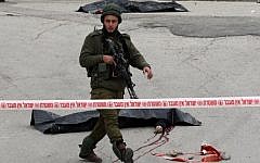 An Israeli solider guards the bodies of two Palestinians who were killed after wounding an Israeli soldier in a knife attack before being shot dead by troops on March 24, 2016 (AFP / HAZEM BADER)