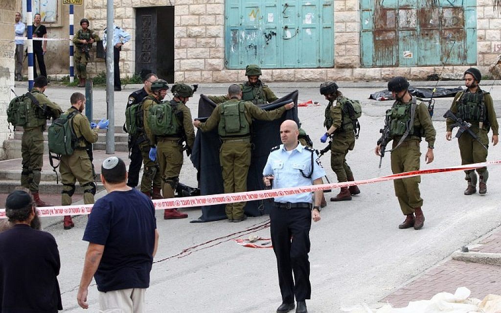 Israeli soldiers cover the body of a Palestinian assailant who was shot in the head by an Israeli soldier as he lay wounded on the ground after injuring an Israeli soldier with a fellow Palestinian attacker in a stabbing assault in Hebron on March 24, 2016. (AFP / HAZEM BADER)