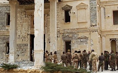 Syrian troops stand next to a mansion belonging to the Qatari royal family in the ancient city of Palmyra on March 24, 2016. (AFP/STR)