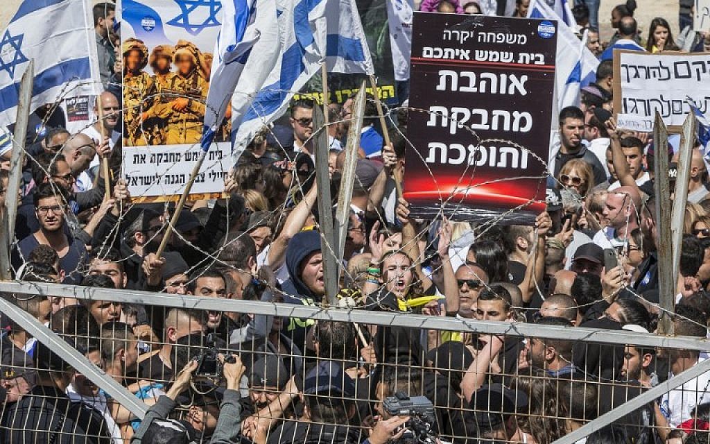 Demonstrators hold banners and flags outside an IDF court hearing in Kiryat Malakhi on March 29, 2016, to show their support for a soldier who shot a wounded Palestinian assailant in the head as he lay on the ground. (AFP / JACK GUEZ)
