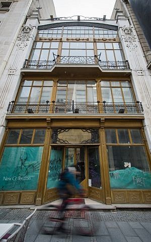 A man cycles by a former department store in Belgrade, that was owned by Jews before the WWII and confiscated by Nazis, March 15, 2016. (AFP/ANDREJ ISAKOVIC)