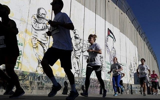 Participants run along Israel's security barrier in the West Bank town of Bethlehem during the 4th Palestine Marathon on April 1, 2016. (AFP/Thomas Coex) Participants run along Israel's security barrier in the West Bank town of Bethlehem during the 4th Palestine Marathon on April 1, 2016. (AFP/Thomas Coex)