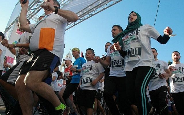Participants run along Israel's security barrier in the West Bank town of Bethlehem during the 4th Palestine Marathon on April 1, 2016. (AFP / THOMAS COEX)