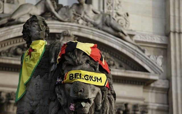 A Belgian flag is draped on a sculpture at a makeshift memorial on the Place de la Bourse (Beursplein) in Brussels on March 23, 2016, a day after blasts hit the Belgian capital. (AFP PHOTO/KENZO TRIBOUILLARD)