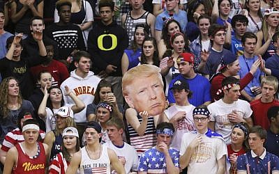 In this Friday, Feb. 26, 2016 photo, the Andrean High School student section holds up a picture of GOP presidential candidate Donald Trump during their school's basketball game against Bishop Noll Institute in Merrillville, Ind. The Catholic bishop in northern Indiana denounced the students who waved the picture of Trump and shouted "build a wall" at their opponents, a heavily Hispanic school in nearby Hammond. (Jonathan Miano/The Times via AP)