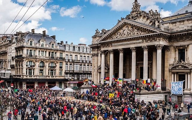 People gather at a memorial site at the Place de la Bourse in Brussels, Sunday, March 27, 2016. In a sign of the tensions in the Belgian capital and the way security services are stretched across the country, Belgium's interior minister appealed to residents not to march Sunday in Brussels in solidarity with the victims. (AP Photo/Geert Vanden Wijngaert)