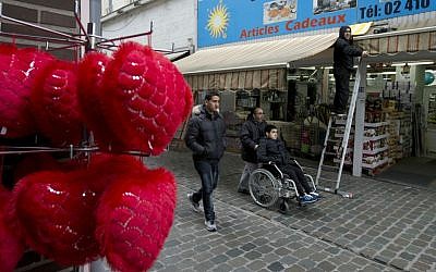 People pass a shop in the Molenbeek neighborhood of Brussels, Belgium, Saturday, March 19, 2016, where fugitive terror suspect Salah Abdeslam was arrested after a four-month manhunt. (AP Photo/Peter Dejong)