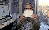 New Yorker cartoon editor Bob Mankoff in his office holding a letter from Rabbi Jill Jacobs’ daughter. (Screenshot from The New Yorker via JTA)