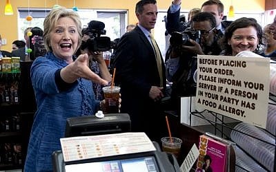 Democratic presidential candidate Hillary Clinton reaches to shake and employees hand behind the counter as she holds her iced tea during a visit to Dunkin' Donuts in West Palm Beach, Fla., Tuesday, March 15, 2016. (AP Photo/Carolyn Kaster)