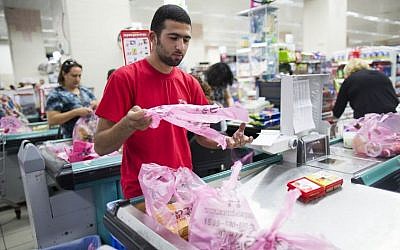 A supermakert worker bagging groceries in plastic bags at the Rami Levi supermarket in Talpiot, Jerusalem, September 3, 2013. (Yonatan Sindel/Flash90)