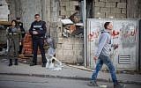Illustrative: A Palestinian man walks past Israeli police officers at the entrance to the Shuafat refugee camp in East Jerusalem on December 2, 2015. (Hadas Parush/Flash90)