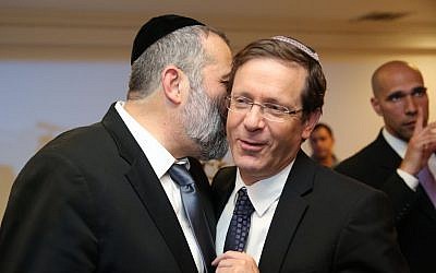 Aryeh Deri, left, whispering to Isaac Herzog at a party in Jerusalem on December 23, 2015. (Yaacov Cohen/FLASH90)