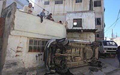 Palestinians look at the debris from clashes between resident and Israeli security forces in the Qalandya refugee camp on March 1, 2016. (Flash90)