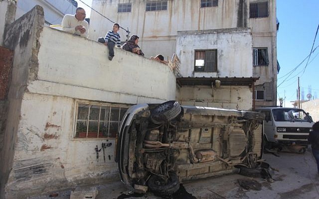 Palestinians look at the debris from clashes between resident and Israeli security forces in the Qalandya refugee camp on March 1, 2016. (Flash90)