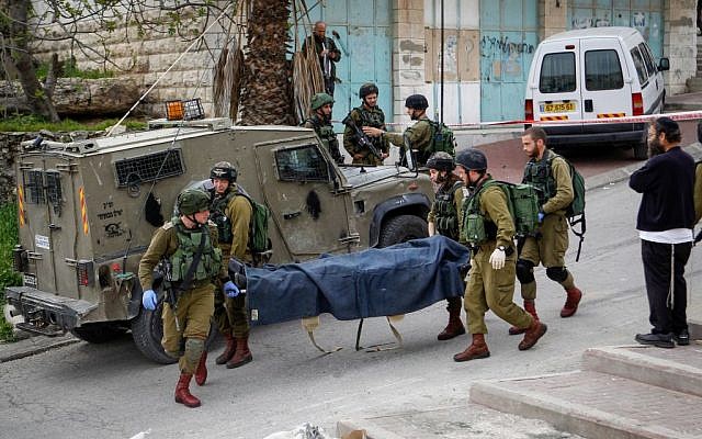 Israeli soldiers remove the body of a Palestinian man shot after he stabbed and wounded a soldier in the West Bank city of Hebron on March 24, 2016. (Wissam Hashlamon/Flash90) Israeli soldiers remove the body of a Palestinian man shot after he stabbed and wounded a soldier in the West Bank city of Hebron on March 24, 2016. (Wissam Hashlamon/Flash90)