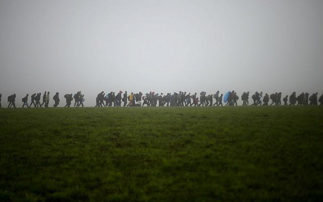 In this Oct. 15, 2015 file photo, a group of migrants make their way over a meadow after crossing the border between Austria and Germany in Wegscheid near Passau, Germany. (AP Photo/Matthias Schrader, file) In this Oct. 15, 2015 file photo, a group of migrants make their way over a meadow after crossing the border between Austria and Germany in Wegscheid near Passau, Germany. (AP Photo/Matthias Schrader, file)