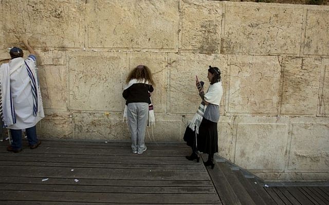 In this photo taken Thursday, Feb. 25, 2016, Reform Rabbi Nicole Greninger, right, takes a picture of other American and Israeli Reform rabbis as they pray in the Western Wall, the holiest site where Jews can pray in Jerusalem's old city. A recent gathering of American Reform rabbis in Jerusalem was meant to celebrate the small gains the liberal Jewish movement has made in Israel in recent years. But a series of comments by Israeli leaders denigrating the group marred the event, reflecting an awkward relationship that many fear is alienating the world’s second-largest Jewish community from Israel. (AP Photo/Sebastian Scheiner)