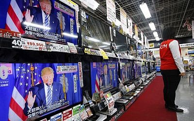 A salesclerk stands in front of flat-panel TVs showing Republican's front-runner candidate Donald Trump in a news program on the US presidential election at an electronics store in Tokyo, March 2, 2016. (AP/Shizuo Kambayashi)