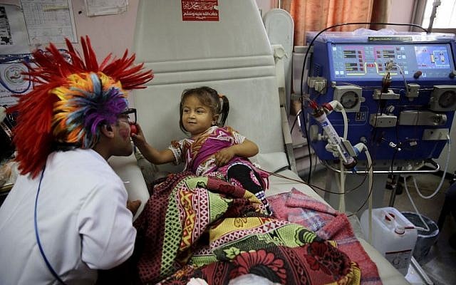 33-year-old Palestinian clown doctor Alaa Miqdad, left, entertains 3-year-old patient Yaqin Shawaf, who suffers from dialysis, in the department of kidney diseases at Al-Rantisi children’s hospital in Gaza City, March 17, 2016. (AP/Adel Hana)