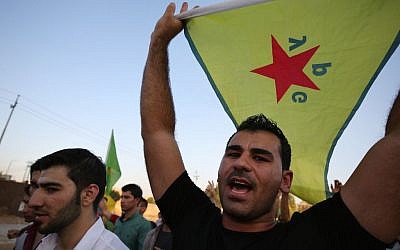 In this Saturday, July 25, 2015 file photo, a demonstrator waves the People's Protection Units flag, known as YPG, which is the main Kurdish fighting force in Syria, during a demonstration in Irbil, the Northern Kurdish region of Iraq. (AP Photo/Bram Janssen)