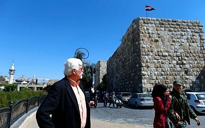 In this picture taken Monday, Feb. 29, 2016, photo Thomas Webber, 71, left, looks at the Citadel of Damascus as a Syrian army soldier walks with his girlfriend in the Syrian capital. (AP Photo/Hassan Ammar)