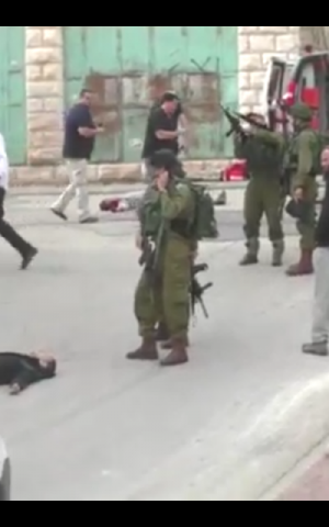 An IDF soldier loading his weapon before he appears to shoot a disarmed, prone Palestinian assailant in the head following a stabbing attack in Hebron on March 24, 2016. (Screen capture: B'Tselem)