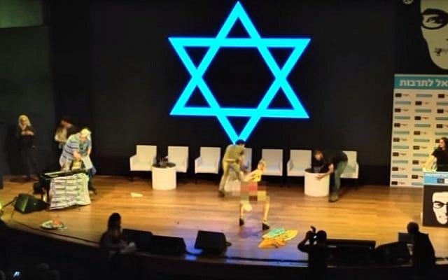 Artist Ariel Bronz getting personal with a flag at a Haaretz conference in Tel Aviv on March 6, 2016. (Screen capture: YouTube/Haaretz) Artist Ariel Bronz getting personal with a flag at a Haaretz conference in Tel Aviv on March 6, 2016. (Screen capture: YouTube/Haaretz)