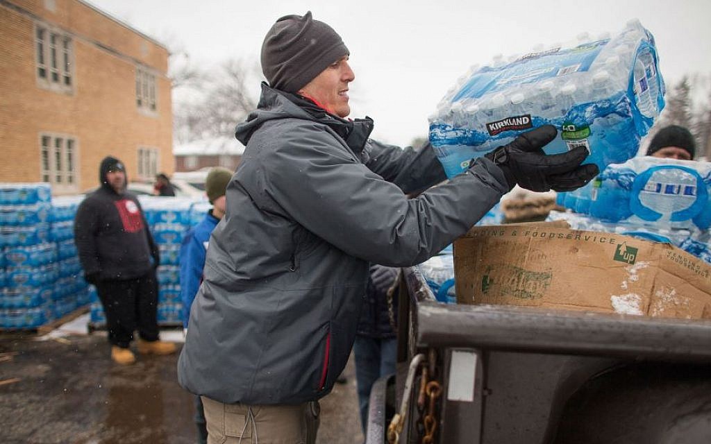 Volunteers loading cases of free water into waiting vehicles at a water distribution center in Flint, Michigan, March 5, 2016. (Geoff Robins/AFP/Getty Images/via JTA) Volunteers loading cases of free water into waiting vehicles at a water distribution center in Flint, Michigan, March 5, 2016. (Geoff Robins/AFP/Getty Images/via JTA)
