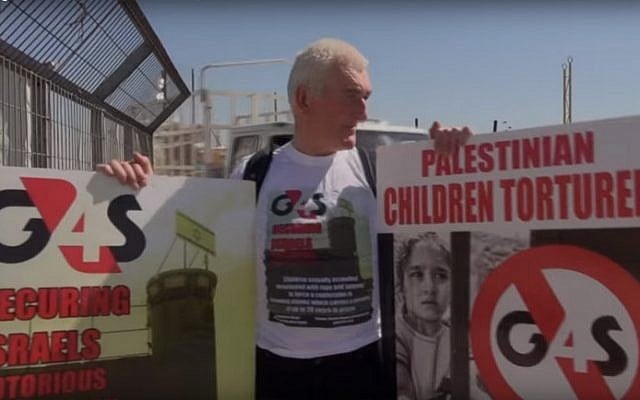 A protester holds posters against the G4S security company outside Israel's Ofer Prison in May 2013 (screen capture: YouTube) A protester holds posters against the G4S security company outside Israel's Ofer Prison in May 2013 (screen capture: YouTube)