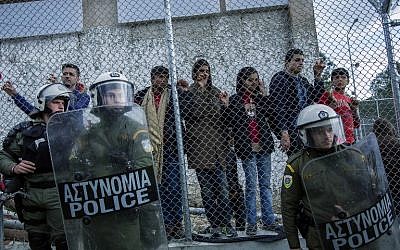 Greek police stand guard in front of the Moria camp while refugees demonstrate against the new deal between EU and Turkey, on March 24, 2016 in Lesbos, Greece. (AFP/Fabio Bucciarelli)