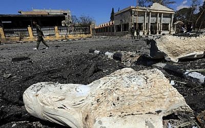 A Syrian soldier walks past the remains of a statue in a heavily damaged street in the ancient Syrian city of Palmyra on March 31, 2016 (AFP / JOSEPH EID)