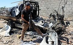 A member of Iraqi government forces inspects a burnt vehicle with a flag of the Islamic State (IS) on its top after they retook an area from jihadists on April 2, 2016 in the village of Al-Mamoura, near Hit, a Euphrates Valley town located about 145 kilometers west of Baghdad in the western province of Anbar. (Moadh al-Dulaimi/AFP)