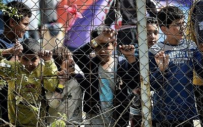 Children stand behind a fence inside the Moria migrant camp transformed in police-run detention facility in Mytilene, on Lesbos island on April 3, 2016. (AFP / ARIS MESSINIS) Children stand behind a fence inside the Moria migrant camp transformed in police-run detention facility in Mytilene, on Lesbos island on April 3, 2016. (AFP / ARIS MESSINIS)