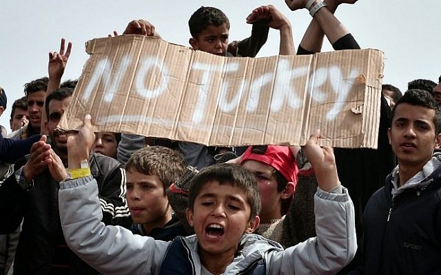 Refugees and migrants including children who left the Chios registration camp, shout slogans and hold placards reading "'No Turkey" during a protest on April 3, 2016 as they camp out in the port of Chios. (AFP / LOUISA GOULIAMAKI)