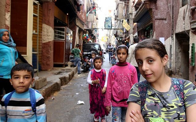 Syrian children pose for a photo on a narrow street in the Shatila Palestinian refugee camp on the southern outskirts of the Lebanese capital, Beirut, on April 5, 2016. (AFP/ANWAR AMRO)
