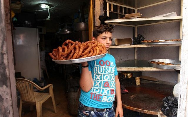 A Syrian boy carries traditional sweets for sale on a street in the Shatila Palestinian refugee camp on the southern outskirts of the Lebanese capital, Beirut, April 5, 2016. (AFP/ANWAR AMRO)
