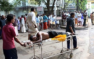 Indian medical officials and bystanders use a trolley to transport an injured man from a vehicle into a hospital in Paravur on April 10, 2016, after an explosion and fire at The Puttingal Devi Temple in the southern Indian state of Kerala. (AFP PHOTO / STR)