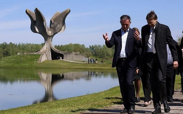 Illustrative: Members of the Jewish community walk in front of a memorial in the shape of a flower in Jasenovac on April 15. 2016. (AFP PHOTO / STRINGER)