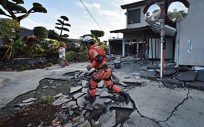 A member of a rescue team runs on a street cracked by the earthquake in Mashiki, Kumamoto prefecture on April 16, 2016. (AFP PHOTO / KAZUHIRO NOGI)