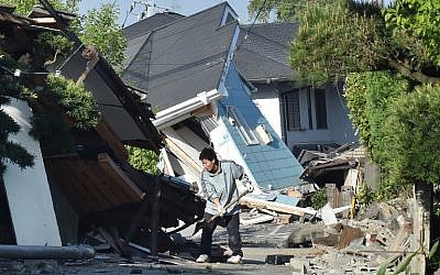 A man clears away debris of a broken wall in Mashiki, Kumamoto prefecture on April 16, 2016, after a powerful earthquake hit southern Japan, the second in two days. (AFP PHOTO/KAZUHIRO NOGI)