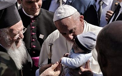 Pope Francis (C) escorted by Patriarch Bartholomew (L) kisses a baby as they arrive at the Moria detaintion center in Mytilene on April 16, 2016. (AFP PHOTO / ARIS MESSINIS)