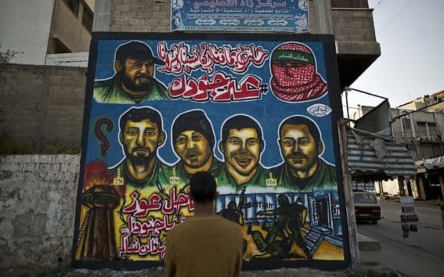 Palestinian men look graffiti marking Palestinian Prisoner Day in Gaza City on April 16, 2016. / AFP PHOTO / MAHMUD HAMS