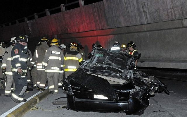 Rescue workers stand before a destroyed car after the collapse of a bridge in an earthquake, in Guayaquil, Ecuador, April 16, 2016. (AFP/MARCOS PIN MENDEZ)
