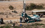 This February 10, 2016, file photo shows IDF soldiers keeping watch as a machine drills holes in the ground on the Israeli side of the border with the Gaza Strip as they search for tunnels used by Palestinian terrorists planning to attack Israel. (AFP/Menahem Kahana)