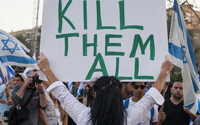 A woman holds up a sign with 'Too many terrorists in prison' written on one side and 'Kill them all' written on the other during a rally in Tel Aviv on April 19, 2016 to support Elor Azaria, an Israeli soldier recently charged with manslaughter after shooting a prone and wounded Palestinian assailant in the head. (Jack Guez/AFP)