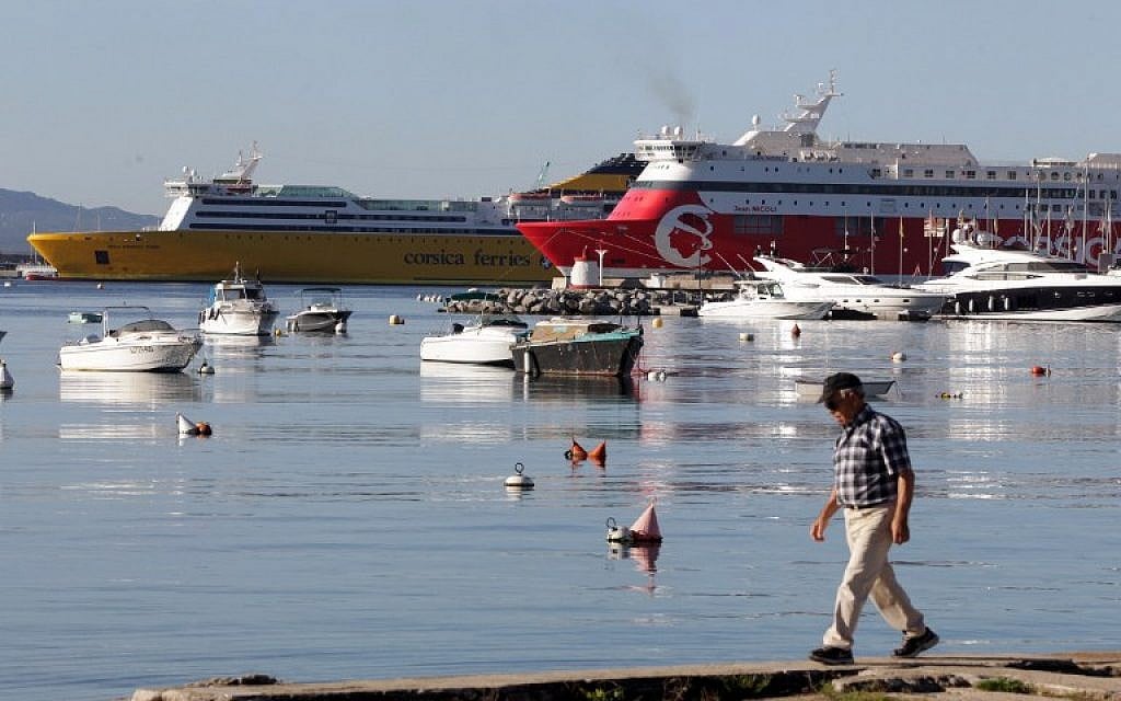 A man walks in front of the Corsica Linea ferry boat Jean Nicoli and a Corsica Ferries boat docked in the Ajaccio's port, on the French Mediterranean island of Corsica. (AFP/PASCAL POCHARD-CASABIANCA)