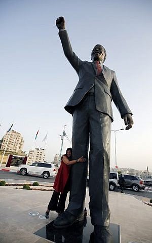 A woman poses in front of a giant statue of Nelson Mandela following its inauguration ceremony in the West Bank city of Ramallah on April 26, 2016. (AFP PHOTO / ABBAS MOMANI)