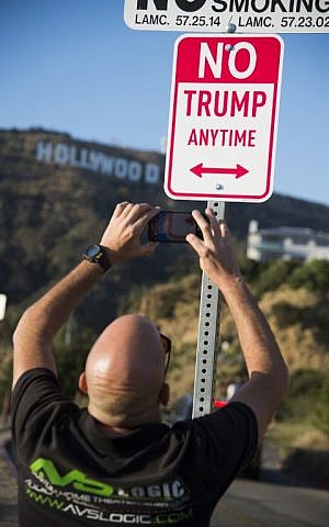 A man photographs a sign reading 'No Trump Anytime' near the iconic 'Hollywood' sign, April 27, 2016, in the hills above Hollywood, California. (AFP PHOTO / ROBYN BECK)